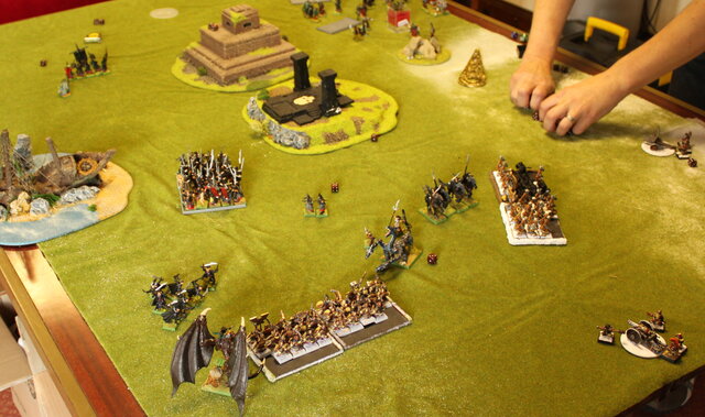 A Warhammer Fantasy game in progress, with regiments of miniatures and terrain on a green tabletop battlefield